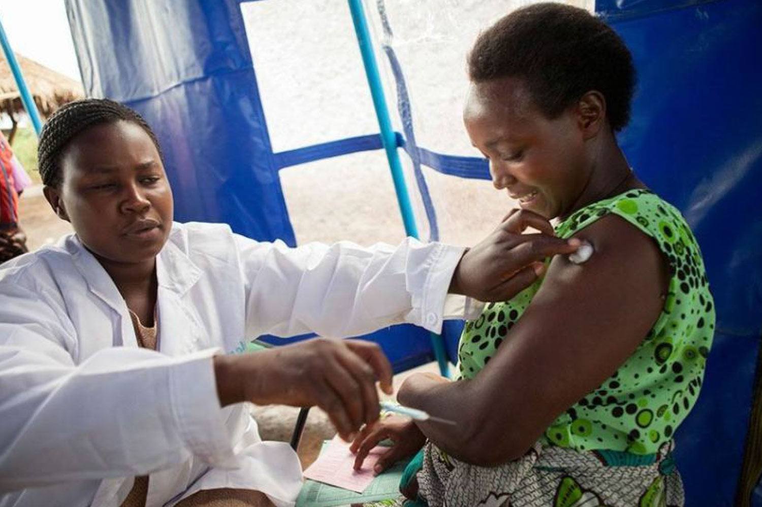 doctor giving a shot to a woman in a green shirt