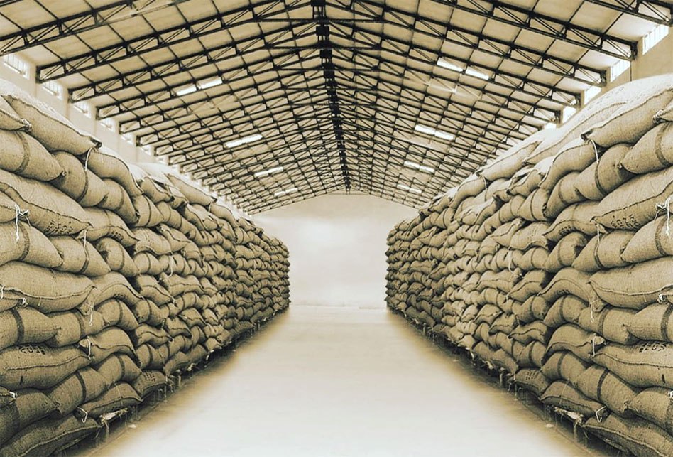 pathway between stacks of coffee beans in brown sacks